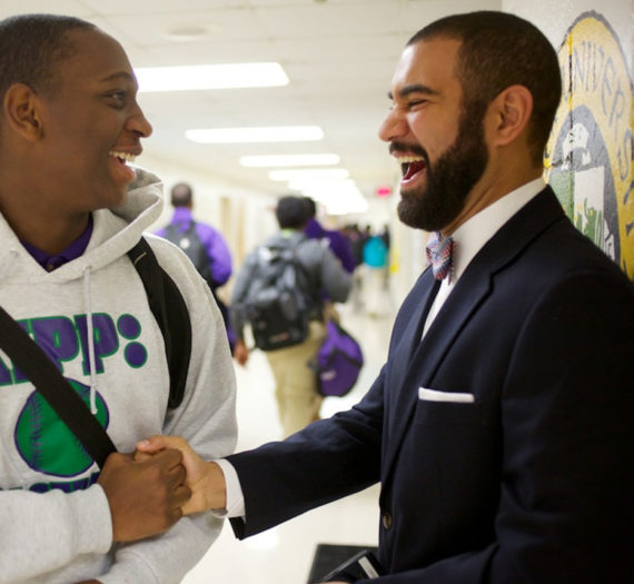 Principal and student shake hands and smile in greeting