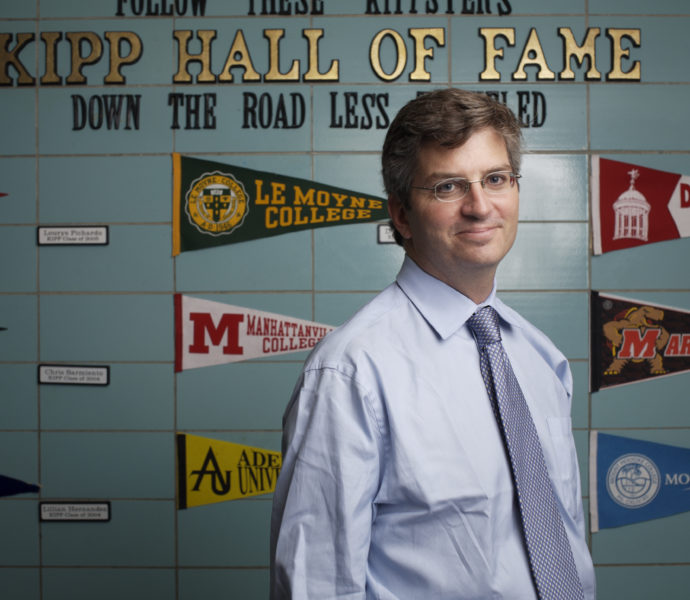 KIPP CEO Richard Barth in front of a wall of college pennants