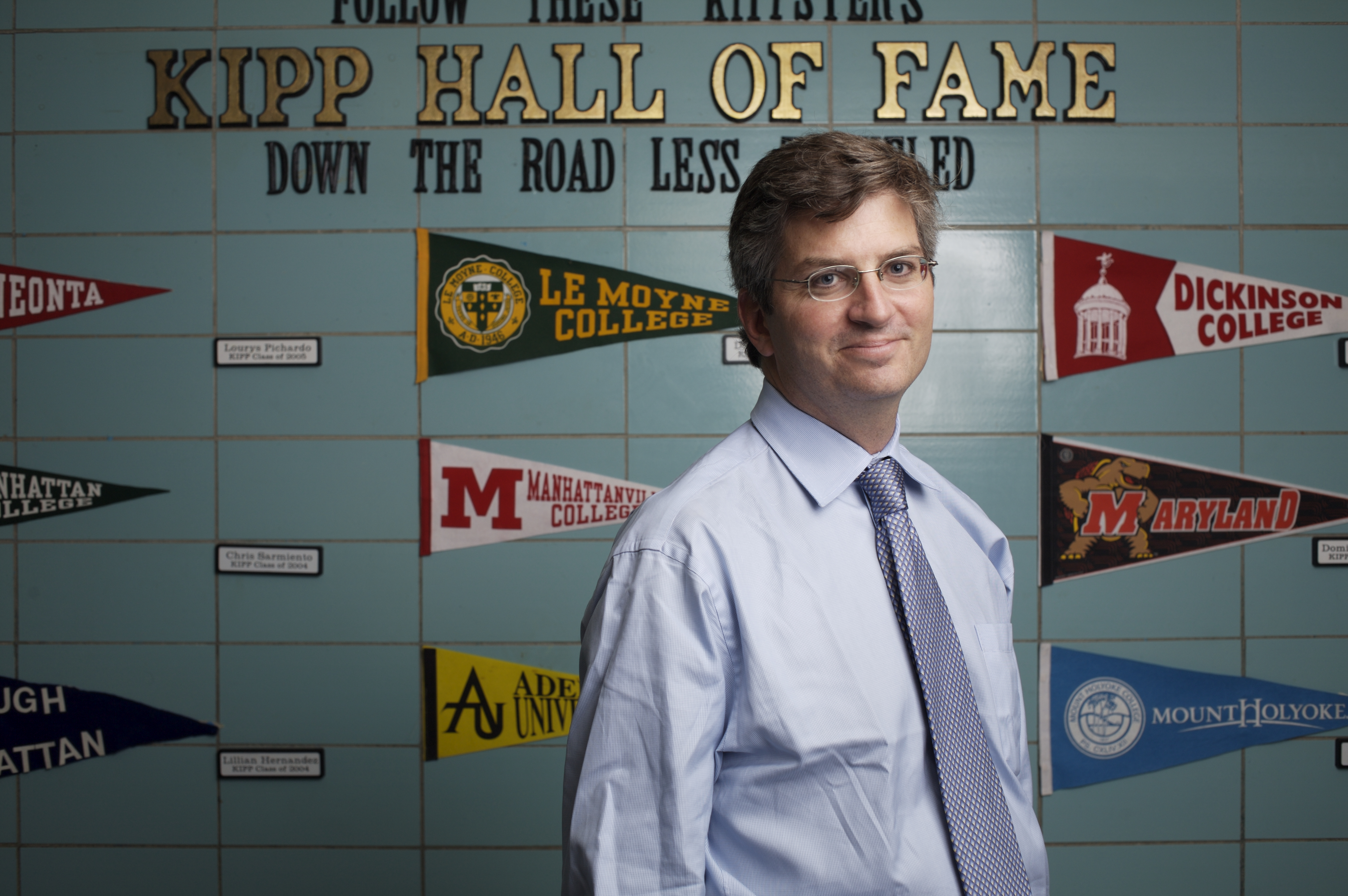KIPP CEO Richard Barth standing in front of a wall of college pennants